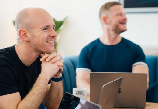 FAQs. Crew members laughing by Apple Mac